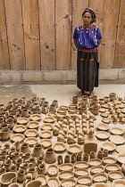 Guatemala, Solola, San Antonio Palopo, A Cakchiquel Mayan woman at her pottery workshop in the traditional dress including the elaborate cinta or hair wrap, woven blue huipil blouse, faja or belt, and...