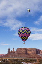 USA, Arizona, Monumnet Valley, Hot air balloons during Balloon Festival fly over Camel Butte in the  Navajo Tribal Park.  The Three Sisters are at left.