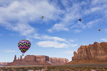 USA, Arizona, Monumnet Valley, Hot air balloons during Balloon Festival fly over Camel Butte in the  Navajo Tribal Park.  The Three Sisters are at left.