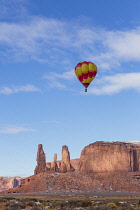 USA, Arizona, Monument Valley, A hot air balloon during Balloon Festival flies in front of the Three Sisters in the Navajo Tribal Park.
