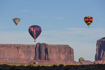 USA, Arizona, Monument Valley, Hot air balloons launch in front of the West Mitten and Sentinal Mesa during Balloon Festival in the Navajo Tribal Park.