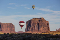 USA, Arizona, Monument Valley, Two hot air balloons fly over the West Mitten, Merrick Butte and Spearhead Mesa during Valley Balloon Festival in the  Navajo Tribal Park.