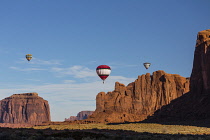 USA, Arizona, Monument Valley, Three hot air balloons fly over the West Mitten, Merrick Butte and Spearhead Mesa during Valley Balloon Festival in the  Navajo Tribal Park.