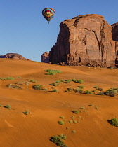 USA, Arizona, Monument Valley, A hot air balloon flying over the red sand dunes at Sand Springs  during Balloon Festival in the  Navajo Tribal Park.