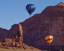 USA, Arizona, Monument Valley, Hot air balloons during Balloon Festival in the  Navajo Tribal Park.  In the forground at left is the Thumb.