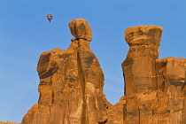 USA, Utah, Arches National Park, A hot air balloon flying near Moab, Utah. In the foreground is the rock formation known as the Three Gossips.