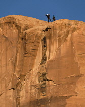 USA, Utah, Moab, A base jumper leaps off the 400 foot vertical face of the Tombstone in Kane Springs Canyon.