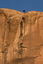 USA, Utah, Moab, A base jumper leaps off the top of the 400 foot vertical face of the Tombstone in Kane Springs Canyon. Note his shadow on the cliff.