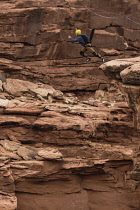 USA, Utah, Moab, A base Jumper leaps off the clifftop 950 feet above the floor of Mineral Canyon.