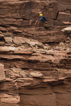 USA, Utah, Moab, A base Jumper leaps off the clifftop 950 feet above the floor of Mineral Canyon.