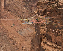 USA, Utah, Moab, Base jumpers prepare to jump from the Mothership Spacenet suspended from the cliffs 950 vertical feet above the valley floor at Mineral canyon.  Another jumper rides the zipline from...