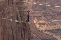 USA, Utah, Moab, A young man slacklining or highlining hundreds of feet above Mineral Canyon during a highline gathering.