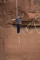 USA, Utah, Moab, A young man slacklining or highlining hundreds of feet above Mineral Canyon during a highline gathering.