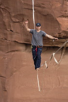 USA, Utah, Moab, A young man slacklining or highlining hundreds of feet above Mineral Canyon during a highline gathering.