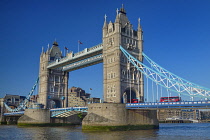 England, London, Tower Bridge viewed from the south bank of the River Thames with an iconic red London bus crossing the bridge.