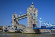 England, London, Tower Bridge viewed from the south bank of the River Thames with an iconic red London bus crossing the bridge.