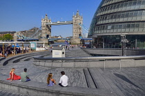 England, London, Tower Bridge with people enjoying Summer sunshine at the Scoop. which is a sunken entertainment amphitheatre next to City Hall.