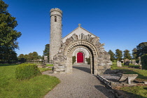 Republic of Ireland, County Kildare, Castledermot, Romanesque doorway in front of St James Church which is Church of Ireland and a 10th century Round Tower in the background.