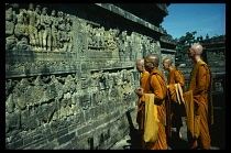 Indonesia, Java, Borobudur, Buddhist monks looking at relief carvings on panels in Buddhist temple complex.