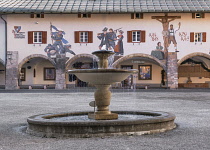 Germany, Bavaria, Berchtesgaden,  Schlossplatz or Castle Square,  A fountain with Luftlmalerei which are Bavarian tree dimensional painted wall frescoes depicting historical scenes such as the tragedy...