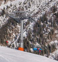 Germany, Bavaria, Berchtesgaden, Berchtesgadener Alps, Jennerbahn chairlift in transit to the summit of the Jenner Mountain with skiers on board.