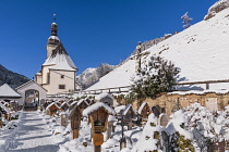 Germany, Bavaria, Ramsau village,  The Church of  St Sebastian with its graveyard in a snow covered landscape.