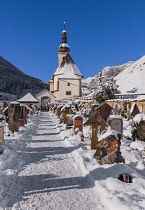 Germany, Bavaria, Ramsau village,  The Church of  St Sebastian with its graveyard in a snow covered landscape.