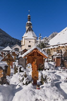 Germany, Bavaria, Ramsau village,  The Church of  St Sebastian with its graveyard in a snow covered landscape.