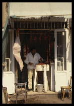 Egypt, Halal butcher with meat hanging in the doorway.