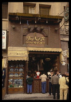 Egypt, Cairo, Khan al-Khalili, Bazaar shop front with people standing by the open counter.