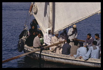 Egypt, Aswan, People in a local ferry on the Nile with sail and oarsmen.
