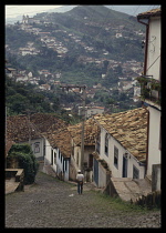 Brazil, Ouro Preto, View from the top of a steep cobbled hillside street lined with houses over the rooftops toward the rest of the town.