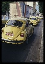 Brazil, Amazonas, Manaus, Row of yellow VW Beetle taxis.