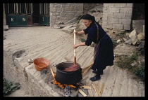 Greece, Epiros, Metsovo, Woman dying wool in cauldron over wood fire.