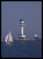 Germany, Baltic, Kiel Canal, Lighthouse near canal entrance and passing yacht.