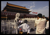 China, Beijing , Tiananmen Square, Chinese tourists having their photograph taken in front of lion statue.