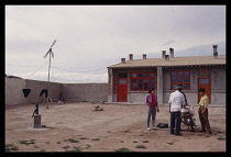 Mongolia, Environment, Wind Power, Electricity generating wind pump outside Mongolian house with group of people and motorcycle beside it.