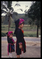 China, Hainan Island, Children, Miao girls wearing mixture of traditional and Western dress, standing looking to the right. .