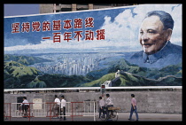 China, Guangdong Province, Shenzhen, Hoarding with portrait of Deng Xiaoping and vision of a modern city with text that reads Uphold the partys fundamental line - we will not waver in a hundred years.