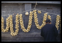 China, Linxia, Woven bamboo cricket cages strung together and hung up for sale along a brick wall.