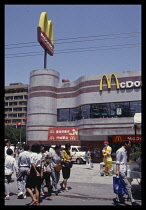 China, Beijing, McDonalds fast food resturant with life size Ronald McDonald figurine standing outside and passers by.