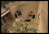 China, Shaanxi, Near Xian, Loess cave houses carved out of soft soil with man walking in courtyard.