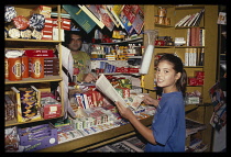 Greece, Attica, Athens, Young girl buying newspaper from kiosk.