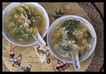China, Food, 2 bowls of Egg Flower Soup on embroidered cloth.