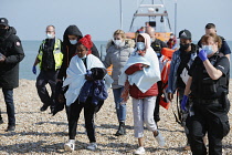 England, Kent, Dungeness, Immigration officers escorting recently landed migrants to be processed.