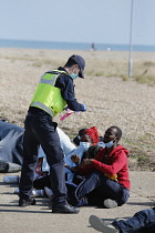 England, Kent, Dungeness, Migrants being searched by immiragtion officers on the beach.