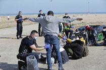 England, Kent, Dungeness, Migrants being searched by immiragtion officers on the beach.