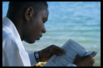 Tanzania, Zanzibar Island, Zanzibar, Young man learning English from a book.