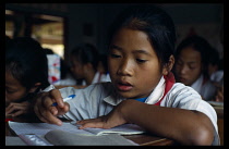 Laos, Children, School, Student at rural girls school writing at her desk.