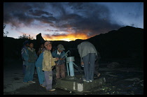 China, Tibet, Shigatse, Group of school children collecting water from the school pump at sunset.